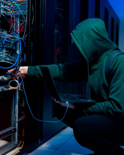 IT-sikkerhet i fokus - serverrom med mann i hettegenser - hacker