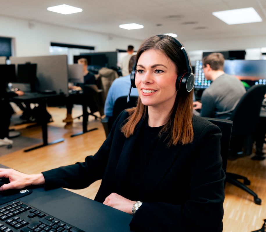 ECIT IT support woman smiling with headphones in front of her computer